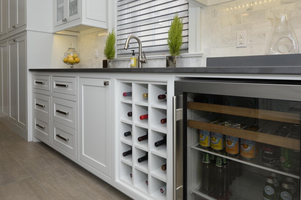 Esempio di una cucina minimalista con lavello integrato, ante gialle, top in quarzite, paraspruzzi bianco, elettrodomestici in acciaio inossidabile, pavimento marrone e top nero