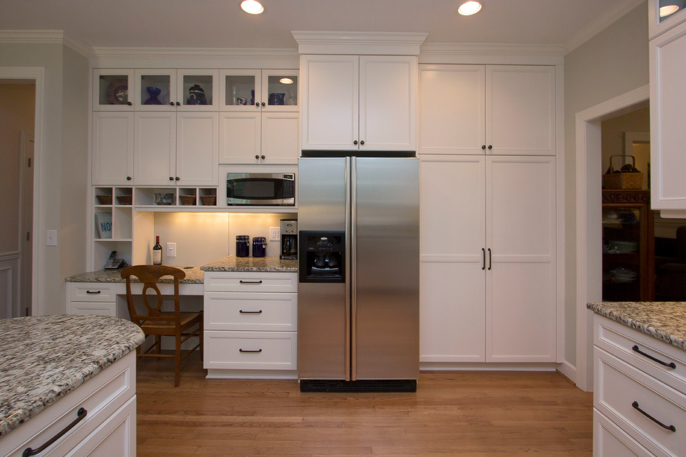 Inredning av ett klassiskt mellanstort flerfärgad flerfärgat kök, med en undermonterad diskho, luckor med infälld panel, vita skåp, granitbänkskiva, grått stänkskydd, stänkskydd i glaskakel, rostfria vitvaror, mellanmörkt trägolv, en halv köksö och orange golv