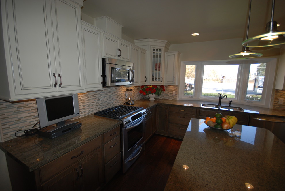 Inredning av ett klassiskt kök, med en undermonterad diskho, luckor med infälld panel, vita skåp, granitbänkskiva, flerfärgad stänkskydd och rostfria vitvaror