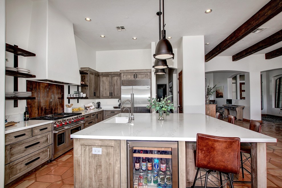 Large urban kitchen/diner in Phoenix with shaker cabinets, distressed cabinets, engineered stone countertops, white splashback, terracotta flooring and an island.