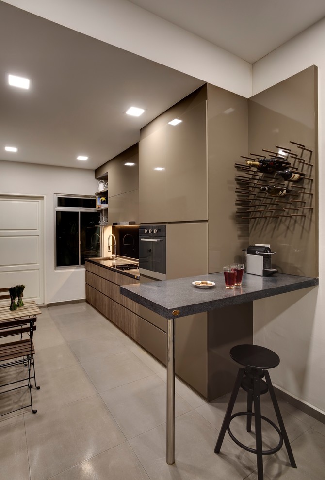 Modern inredning av ett avskilt, litet l-kök, med en undermonterad diskho, släta luckor, bruna skåp, granitbänkskiva, svart stänkskydd, glaspanel som stänkskydd, rostfria vitvaror och en köksö
