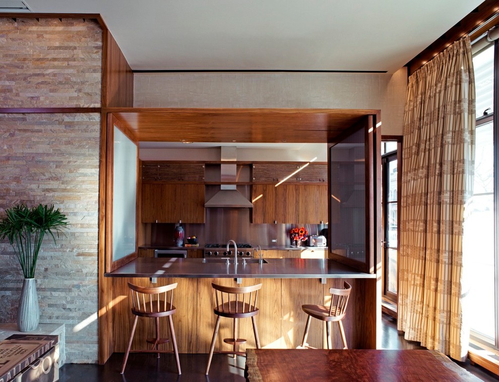 ニューヨークにあるコンテンポラリースタイルのおしゃれなキッチン (一体型シンク、フラットパネル扉のキャビネット、中間色木目調キャビネット、ステンレスカウンター、メタリックのキッチンパネル、シルバーの調理設備) の写真