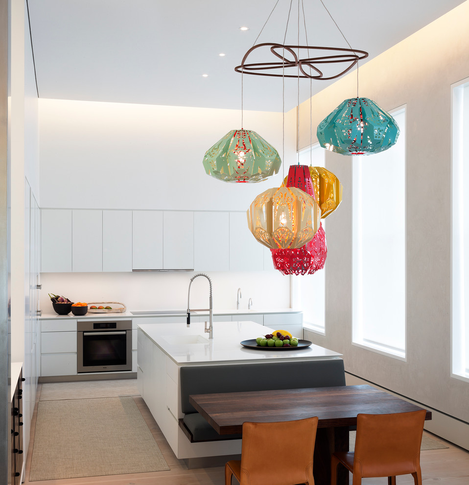 Moderne Küche in L-Form mit flächenbündigen Schrankfronten, weißen Schränken, Küchengeräten aus Edelstahl und Kücheninsel in New York