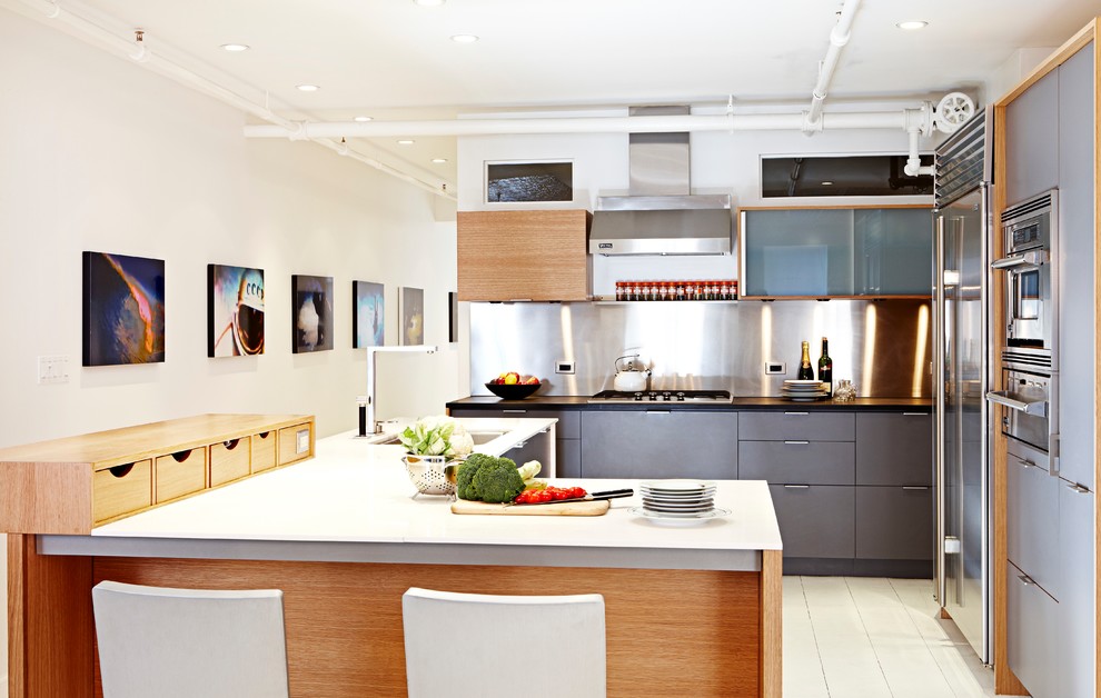 Bild på ett funkis u-kök, med en undermonterad diskho, släta luckor, grå skåp, stänkskydd med metallisk yta, rostfria vitvaror och en köksö