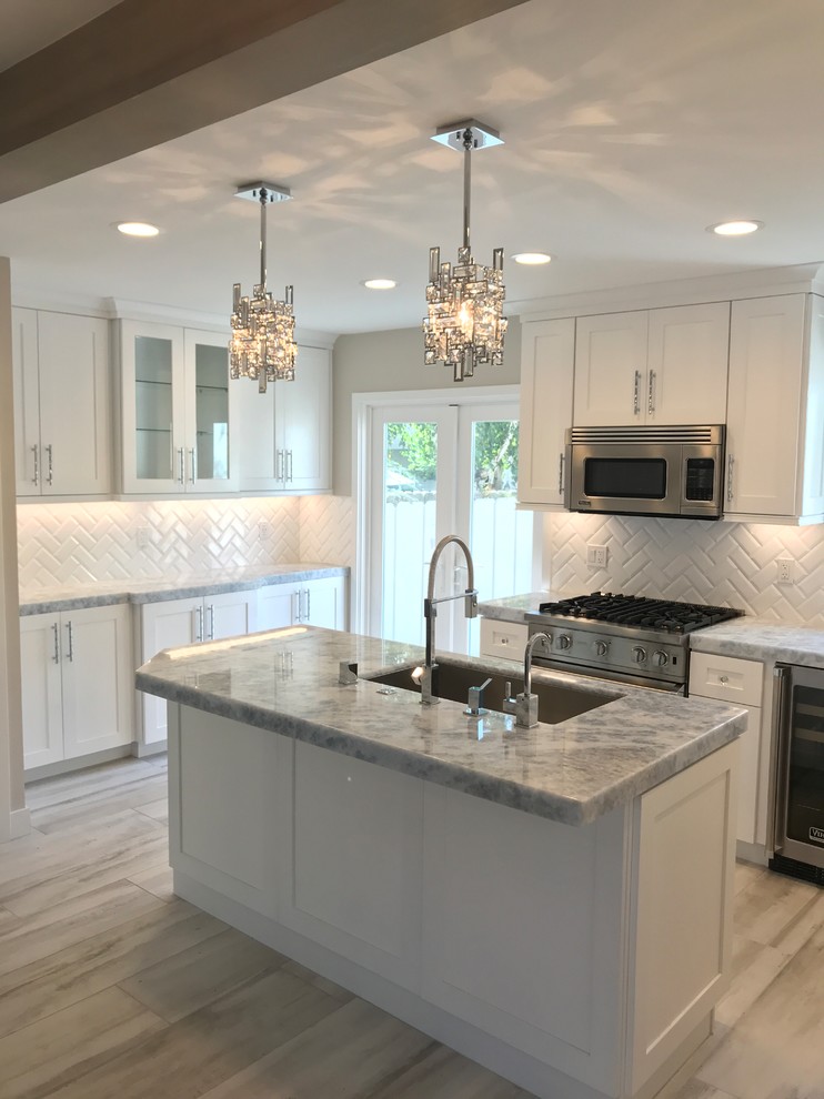 Design ideas for a large classic u-shaped open plan kitchen in San Diego with a submerged sink, shaker cabinets, white cabinets, engineered stone countertops, white splashback, ceramic splashback, stainless steel appliances, porcelain flooring, an island, grey floors and grey worktops.
