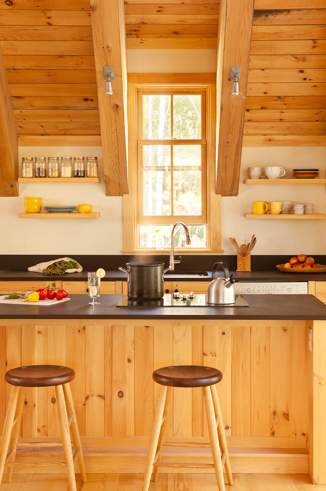 Cette image montre une cuisine ouverte linéaire rustique en bois brun avec un évier encastré, un sol en bois brun, îlot, plan de travail noir, une crédence noire, un électroménager en acier inoxydable, un sol beige et fenêtre au-dessus de l'évier.