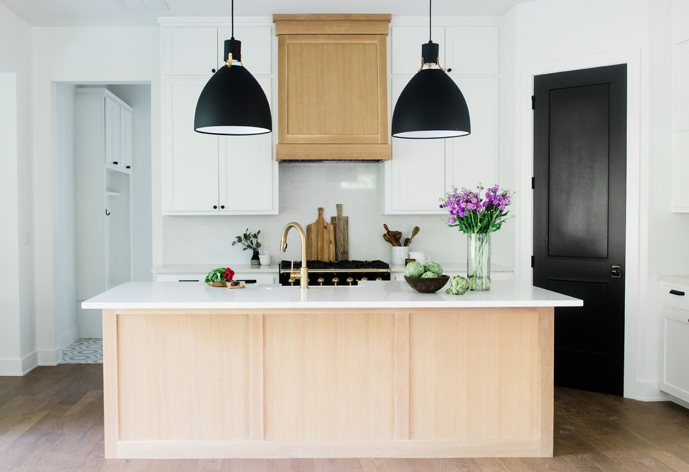 Esempio di una cucina country con ante in stile shaker, ante in legno chiaro, paraspruzzi bianco, elettrodomestici neri, pavimento in legno massello medio, pavimento marrone e top bianco