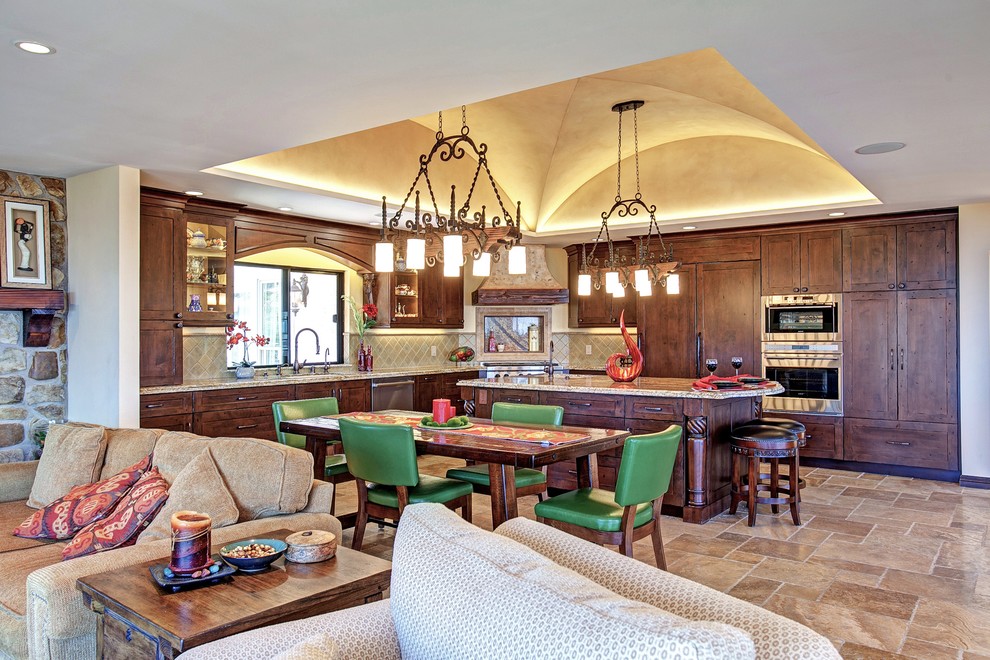 Foto på ett mellanstort medelhavsstil kök, med en köksö, luckor med infälld panel, bruna skåp, granitbänkskiva, grönt stänkskydd, stänkskydd i keramik, integrerade vitvaror och travertin golv