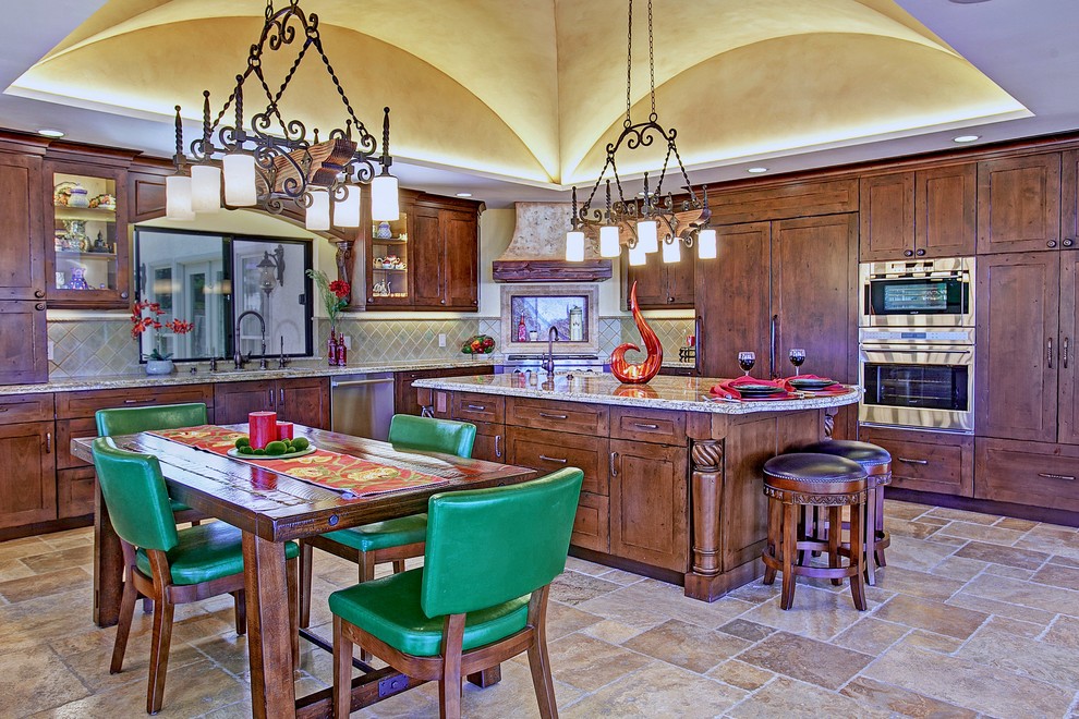 Exempel på ett mellanstort medelhavsstil kök, med en köksö, luckor med infälld panel, bruna skåp, granitbänkskiva, grönt stänkskydd, stänkskydd i keramik, rostfria vitvaror och travertin golv