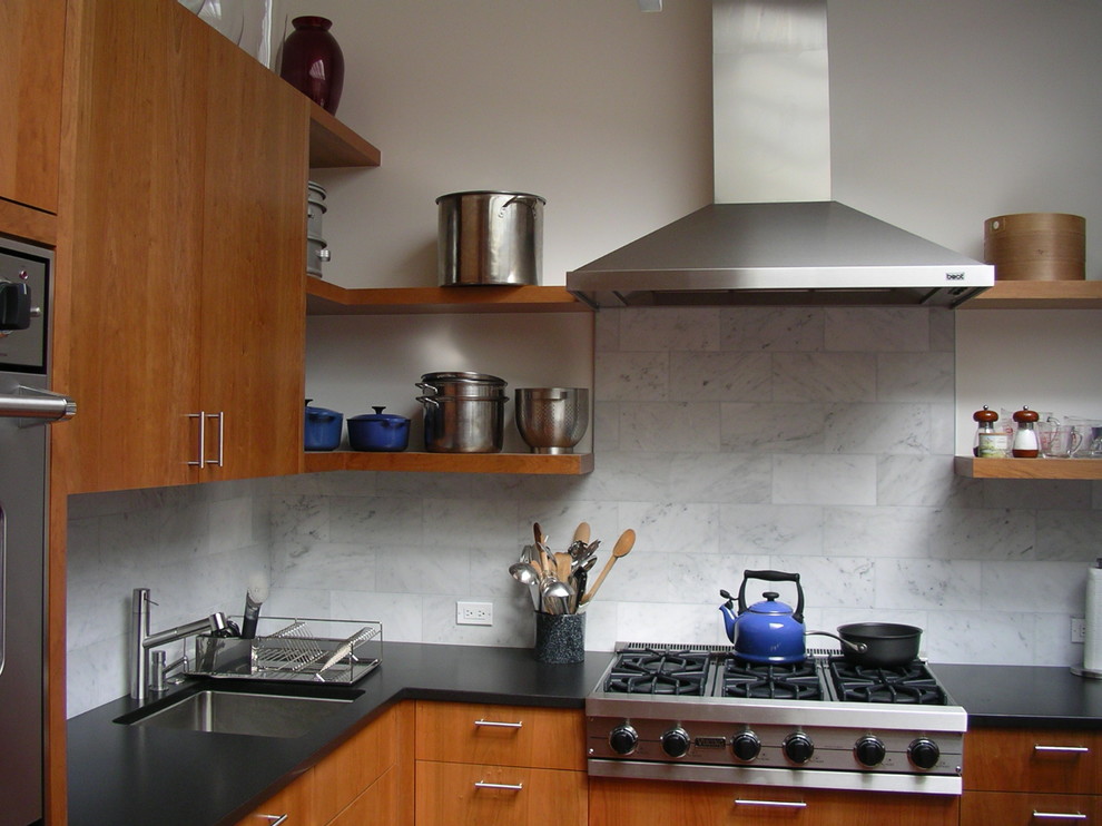 Cette image montre une cuisine design en bois brun avec un électroménager en acier inoxydable, un évier encastré, un placard à porte plane, une crédence blanche et une crédence en marbre.
