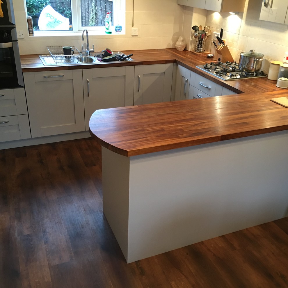 Small minimalist u-shaped vinyl floor eat-in kitchen photo in West Midlands with wood countertops and stainless steel appliances