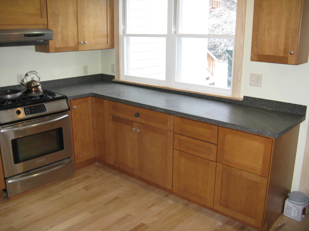 Photo of a small classic l-shaped kitchen/diner in Other with a double-bowl sink, shaker cabinets, medium wood cabinets, laminate countertops, beige splashback, stainless steel appliances, light hardwood flooring and a breakfast bar.