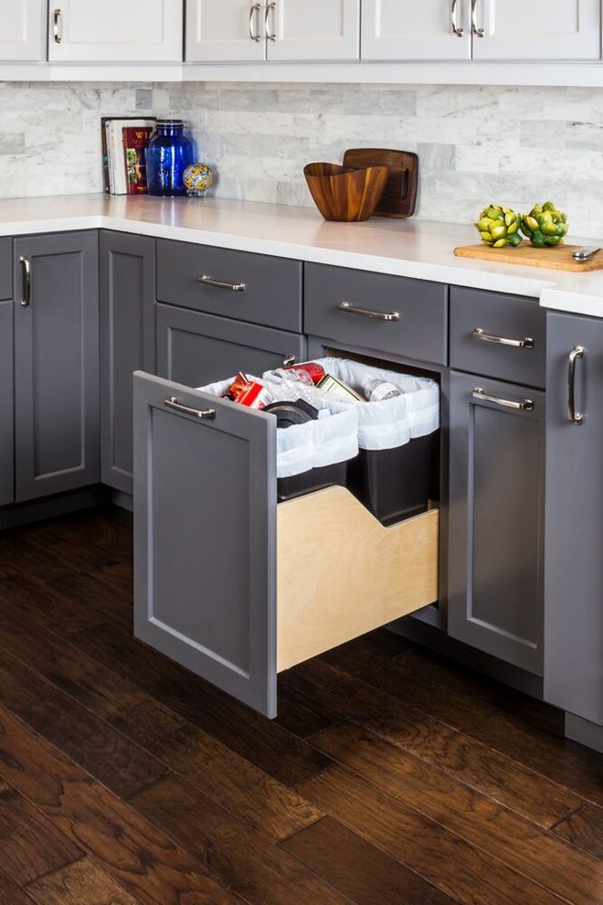 Example of a transitional dark wood floor kitchen design with a farmhouse sink, shaker cabinets, gray cabinets, gray backsplash and stainless steel appliances