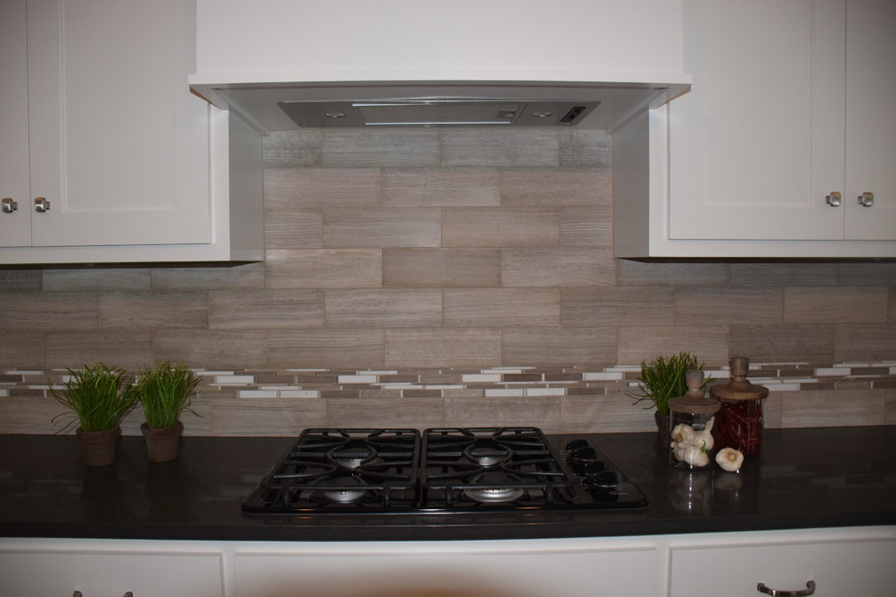 Example of a transitional light wood floor kitchen design in Other with an undermount sink, shaker cabinets, white cabinets, quartzite countertops, gray backsplash, stone tile backsplash, stainless steel appliances and an island