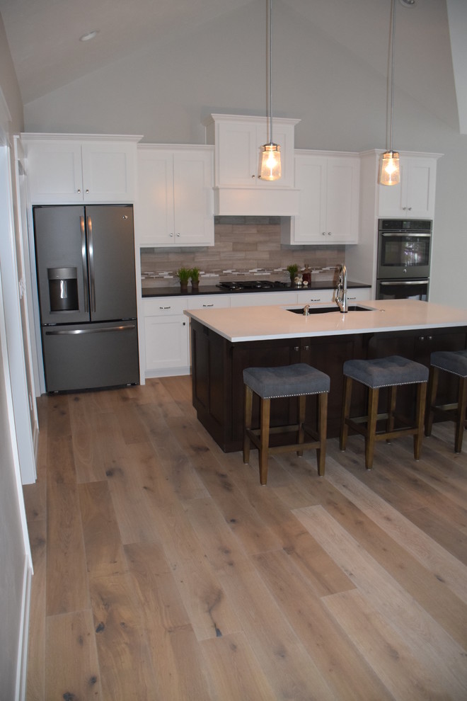 Exempel på ett mellanstort klassiskt linjärt kök med öppen planlösning, med en undermonterad diskho, skåp i shakerstil, vita skåp, bänkskiva i kvartsit, grått stänkskydd, stänkskydd i stenkakel, rostfria vitvaror, en köksö, mellanmörkt trägolv och beiget golv