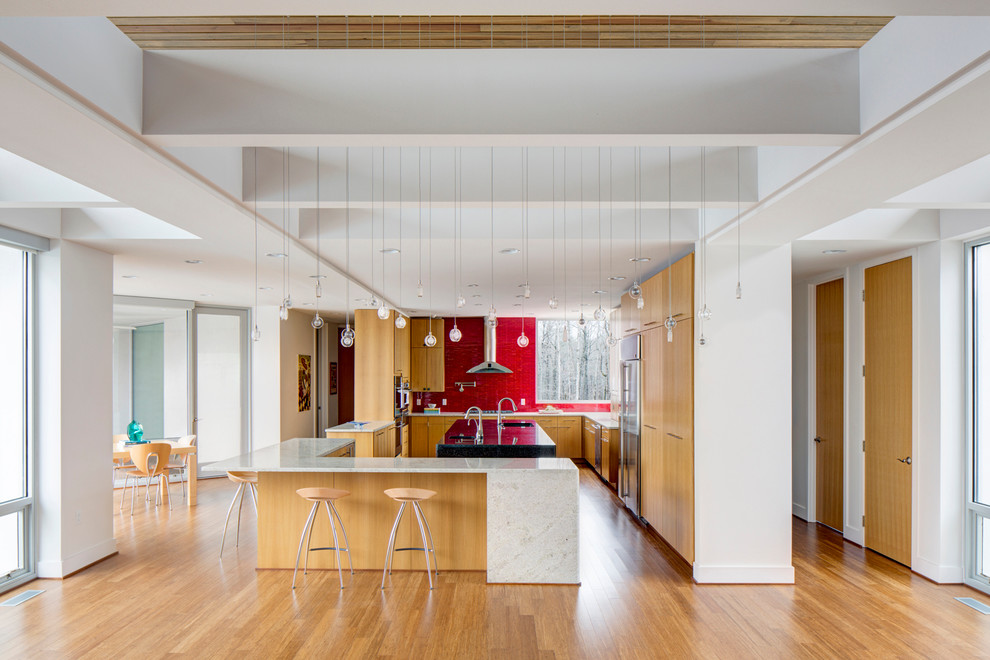 Moderne Wohnküche mit flächenbündigen Schrankfronten, hellen Holzschränken, Küchenrückwand in Rot und Küchengeräten aus Edelstahl in Little Rock