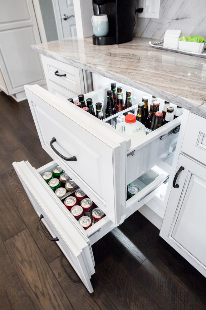 Photo of a large classic kitchen/diner in Cleveland with a submerged sink, raised-panel cabinets, white cabinets, quartz worktops, grey splashback, marble splashback, integrated appliances, dark hardwood flooring, an island, black floors and grey worktops.