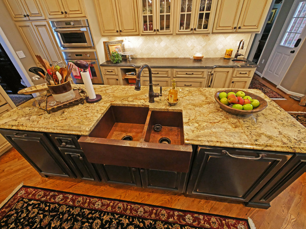 Large elegant galley medium tone wood floor eat-in kitchen photo in Other with an integrated sink, raised-panel cabinets, distressed cabinets, granite countertops, beige backsplash, stone tile backsplash, paneled appliances and an island