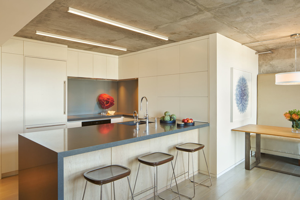 Kleine Moderne Wohnküche in U-Form mit flächenbündigen Schrankfronten, Küchenrückwand in Grau, braunem Holzboden, braunem Boden, beigen Schränken, Elektrogeräten mit Frontblende, Halbinsel und Unterbauwaschbecken in San Francisco