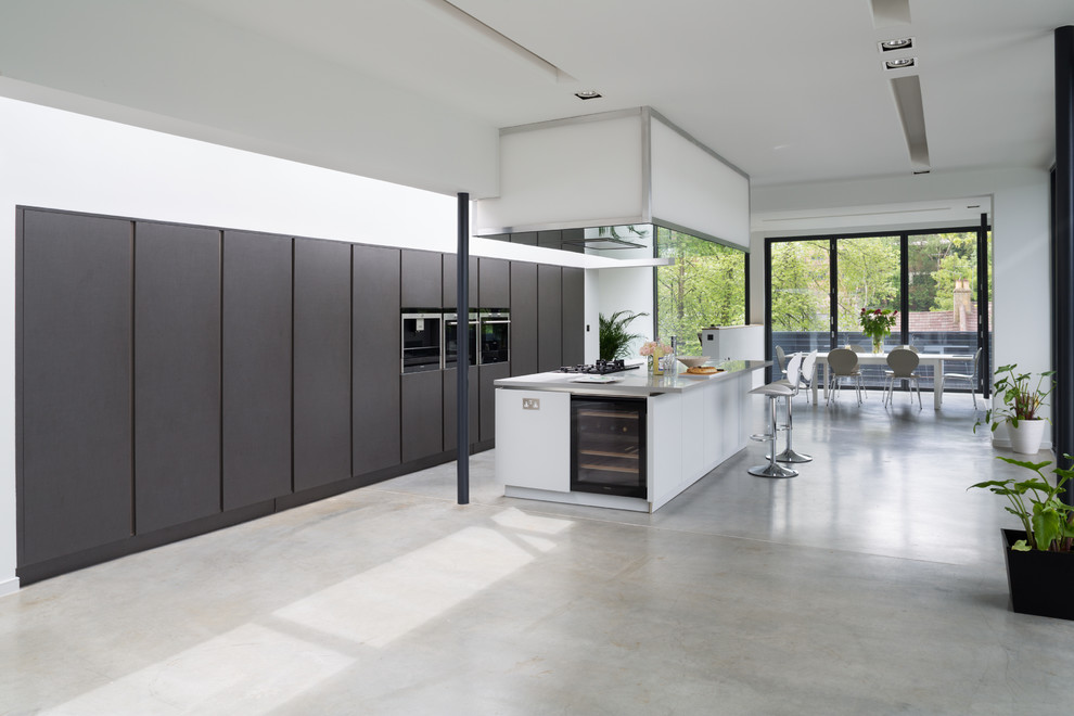 Exempel på ett mycket stort modernt kök, med en integrerad diskho, släta luckor, bänkskiva i betong, rostfria vitvaror, betonggolv och en köksö