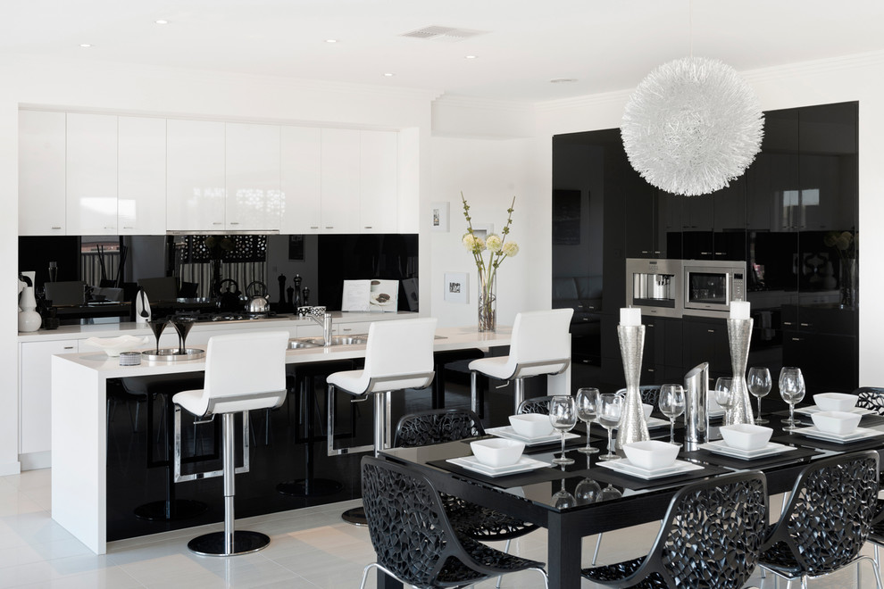 Стильный дизайн: параллельная кухня в современном стиле с обеденным столом, плоскими фасадами, черным фартуком, фартуком из стекла, островом и черно-белыми фасадами - последний тренд