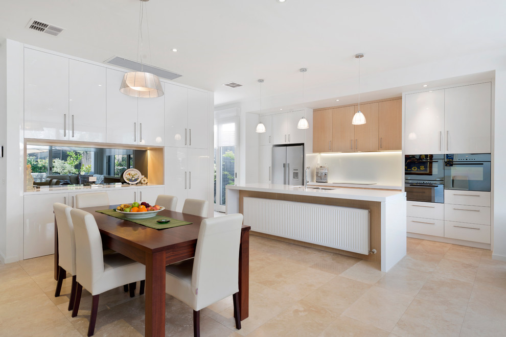 Ejemplo de cocina comedor contemporánea con armarios con paneles lisos, puertas de armario blancas, electrodomésticos de acero inoxidable y una isla