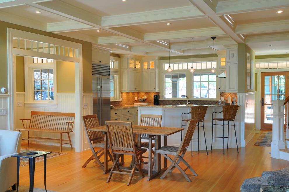 На фото: угловая кухня-гостиная в классическом стиле с фасадами в стиле шейкер, бежевыми фасадами и техникой из нержавеющей стали