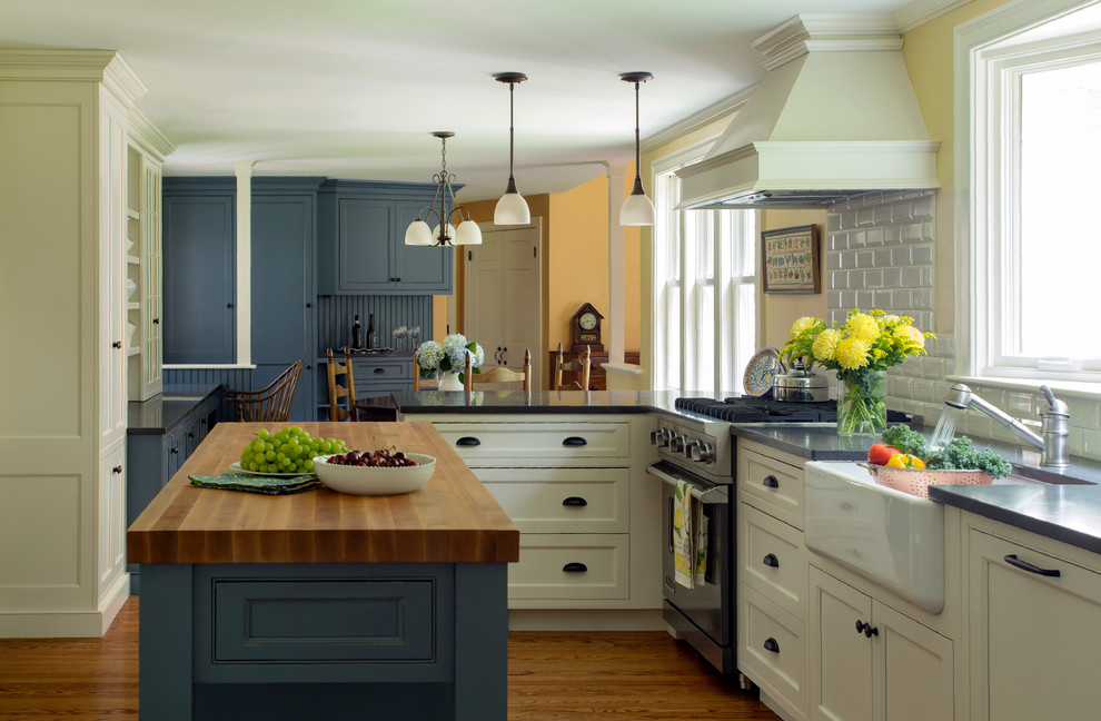 Lantlig inredning av ett stort kök, med en rustik diskho, vitt stänkskydd, rostfria vitvaror, mellanmörkt trägolv, en köksö, skåp i shakerstil, blå skåp, träbänkskiva och stänkskydd i keramik