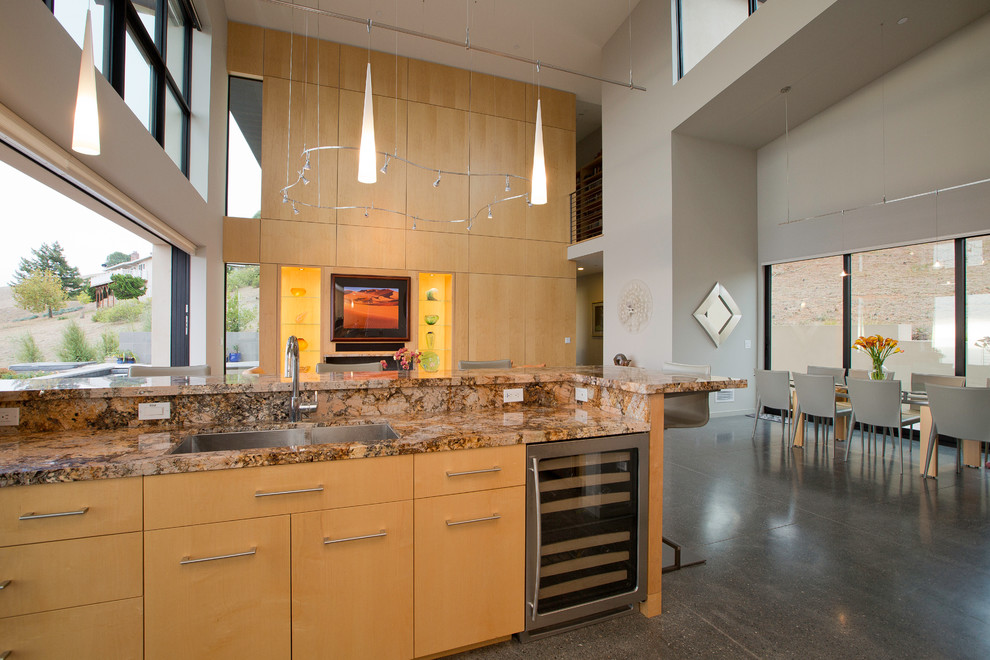 Свежая идея для дизайна: кухня-гостиная в стиле модернизм с врезной мойкой, светлыми деревянными фасадами, плоскими фасадами и техникой из нержавеющей стали - отличное фото интерьера
