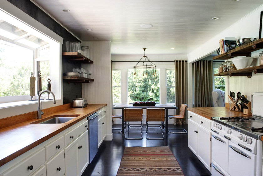 Modern inredning av ett mellanstort kök, med en undermonterad diskho, luckor med infälld panel, vita skåp, träbänkskiva, stänkskydd med metallisk yta, stänkskydd i metallkakel, rostfria vitvaror och mörkt trägolv