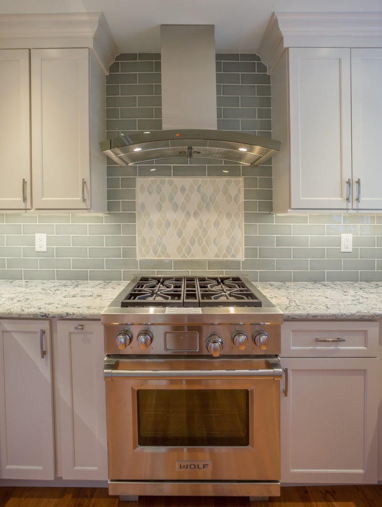 Mid-sized trendy u-shaped medium tone wood floor and brown floor kitchen photo in Wilmington with a farmhouse sink, shaker cabinets, white cabinets, quartzite countertops, green backsplash, subway tile backsplash, stainless steel appliances, an island and multicolored countertops