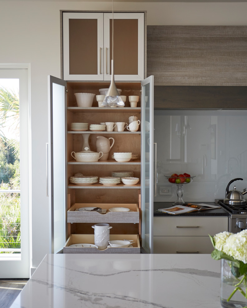 Foto de cocina actual de tamaño medio con fregadero bajoencimera, armarios con paneles lisos, puertas de armario grises, encimera de cuarzo compacto, salpicadero blanco, salpicadero de vidrio templado, electrodomésticos con paneles, suelo de baldosas de porcelana, dos o más islas y suelo marrón