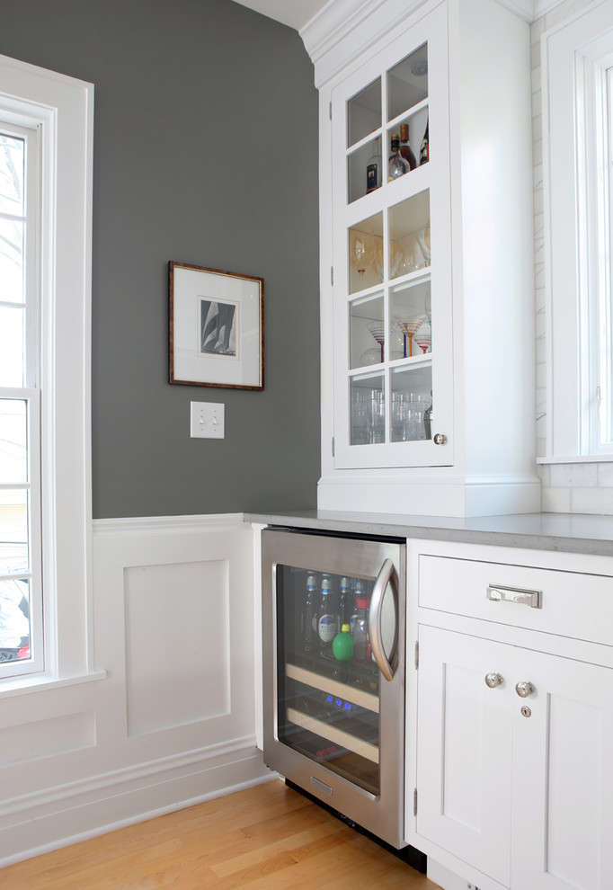 Large elegant galley light wood floor eat-in kitchen photo in Chicago with glass-front cabinets, white cabinets, quartz countertops, gray backsplash, stone tile backsplash, stainless steel appliances and an island