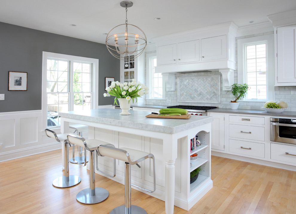 Inspiration for a large timeless galley light wood floor kitchen remodel in Chicago with quartz countertops, white cabinets, gray backsplash, recessed-panel cabinets, stainless steel appliances, an island and marble backsplash