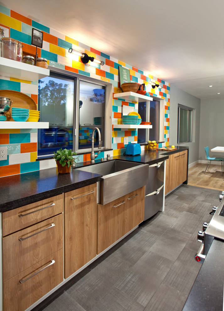 Inspiration for a small modern galley enclosed kitchen in Los Angeles with a belfast sink, flat-panel cabinets, distressed cabinets, engineered stone countertops, multi-coloured splashback, ceramic splashback, stainless steel appliances, porcelain flooring, no island, grey floors and black worktops.
