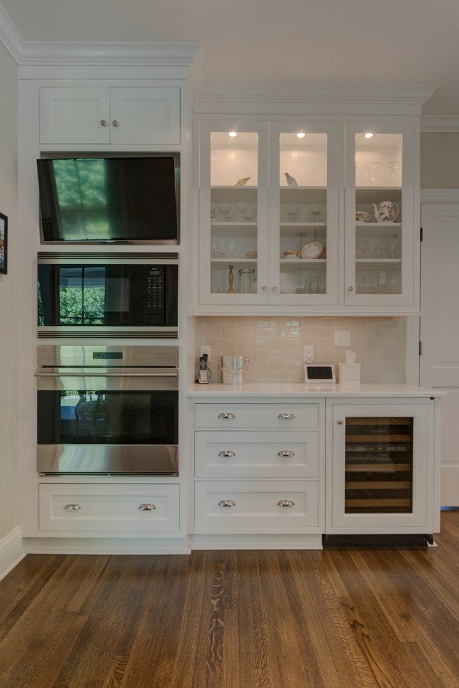 Inspiration för ett avskilt, mellanstort vintage u-kök, med luckor med infälld panel, vita skåp, vitt stänkskydd, integrerade vitvaror, mellanmörkt trägolv, en köksö och brunt golv
