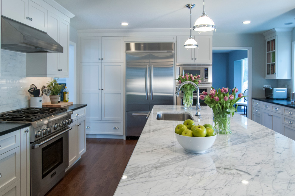 Example of a large transitional l-shaped medium tone wood floor eat-in kitchen design in Philadelphia with an undermount sink, shaker cabinets, white cabinets, granite countertops, white backsplash, stone tile backsplash, stainless steel appliances and an island