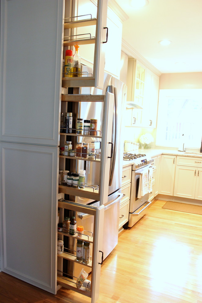 Foto de cocina clásica renovada con armarios con paneles empotrados, encimera de granito, puertas de armario blancas, electrodomésticos de acero inoxidable y suelo de madera clara