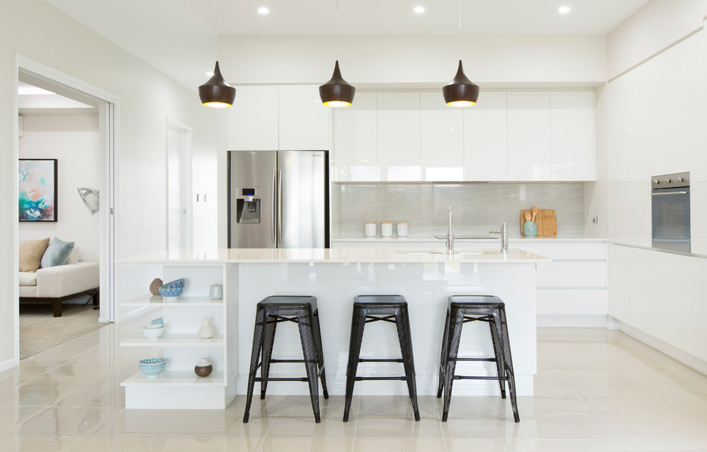 Medium sized contemporary l-shaped open plan kitchen in Townsville with a submerged sink, flat-panel cabinets, white cabinets, engineered stone countertops, grey splashback, porcelain splashback, stainless steel appliances, ceramic flooring and an island.