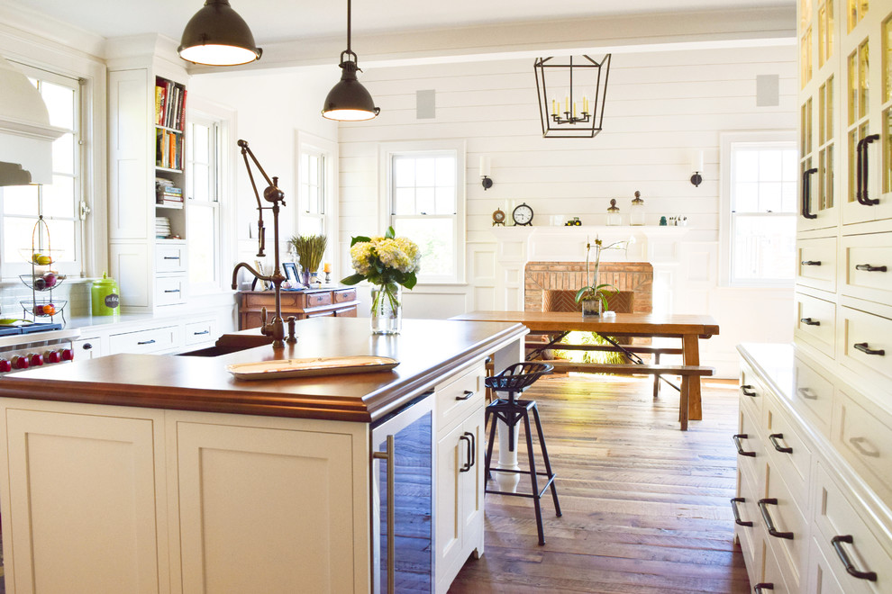 Inspiration for a large country galley medium tone wood floor eat-in kitchen remodel in New York with a farmhouse sink, recessed-panel cabinets, white cabinets, wood countertops, blue backsplash, glass tile backsplash, stainless steel appliances and an island