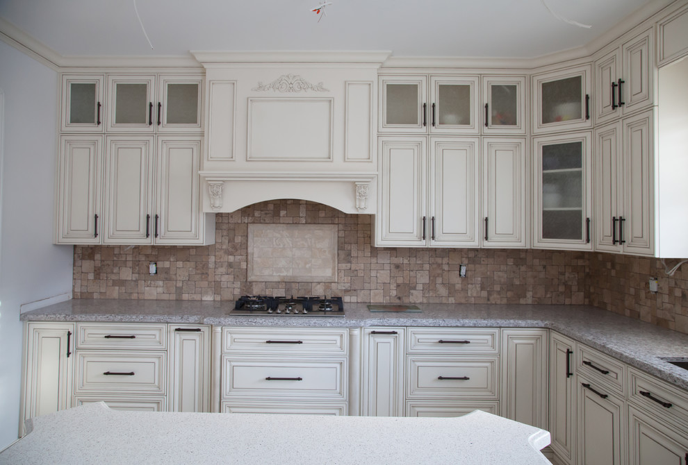 Inredning av ett klassiskt kök, med en enkel diskho, beige skåp, granitbänkskiva, brunt stänkskydd, stänkskydd i stenkakel, rostfria vitvaror, klinkergolv i porslin och en köksö