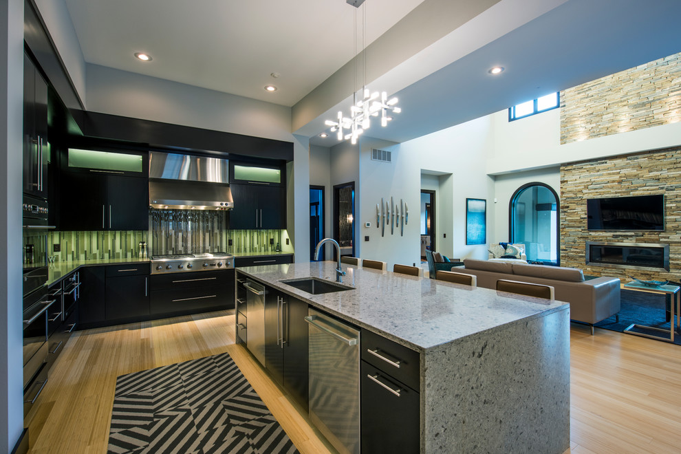 Photo of a large modern l-shaped open plan kitchen in Other with flat-panel cabinets, dark wood cabinets, bamboo flooring, an island, a submerged sink, engineered stone countertops, green splashback, glass tiled splashback and integrated appliances.