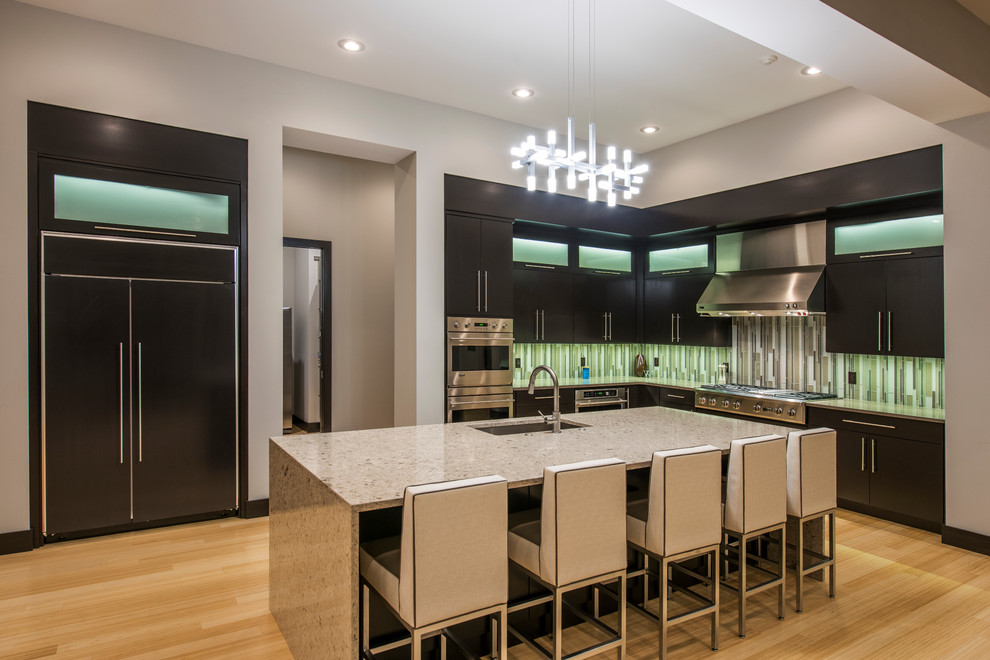 Inspiration for a large modern l-shaped bamboo floor kitchen remodel in Other with an undermount sink, flat-panel cabinets, dark wood cabinets, quartz countertops, an island, green backsplash, glass tile backsplash and paneled appliances