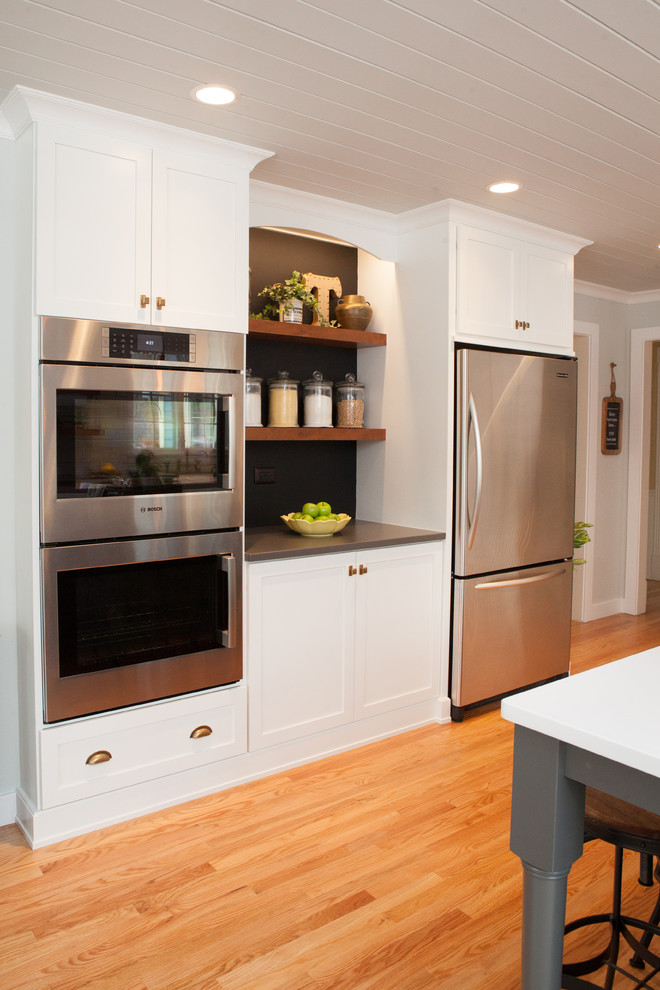 Eat-in kitchen - mid-sized transitional u-shaped light wood floor eat-in kitchen idea in Chicago with a farmhouse sink, recessed-panel cabinets, white cabinets, quartz countertops, multicolored backsplash, subway tile backsplash, stainless steel appliances and an island