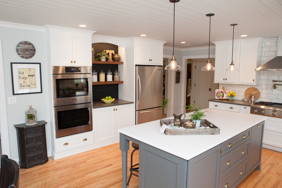Exempel på ett mellanstort klassiskt kök, med en rustik diskho, luckor med infälld panel, vita skåp, bänkskiva i kvarts, flerfärgad stänkskydd, stänkskydd i tunnelbanekakel, rostfria vitvaror, ljust trägolv och en köksö