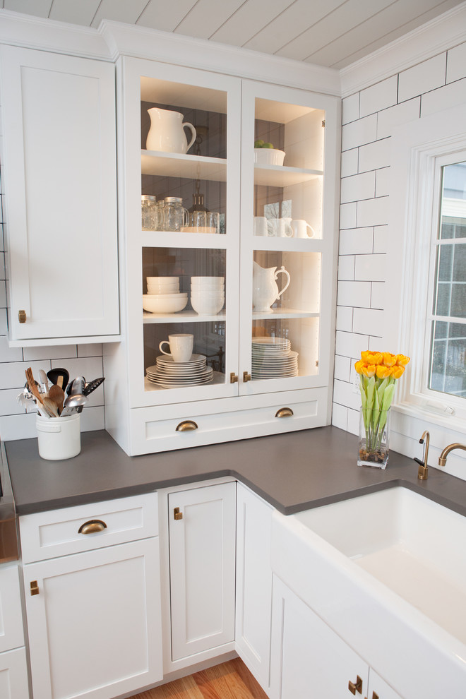 Mid-sized transitional u-shaped light wood floor eat-in kitchen photo in Chicago with a farmhouse sink, recessed-panel cabinets, white cabinets, quartz countertops, multicolored backsplash, subway tile backsplash, stainless steel appliances and an island