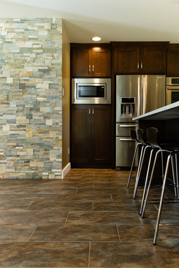 Large transitional ceramic tile and brown floor eat-in kitchen photo in Other with dark wood cabinets, stainless steel appliances and an island