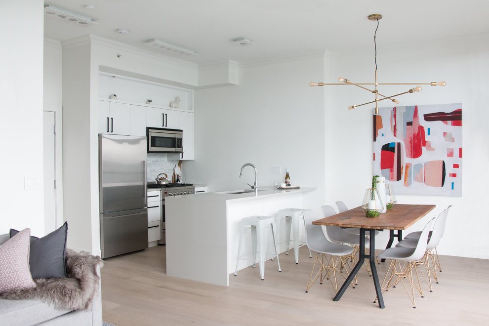 Mid-sized trendy galley light wood floor eat-in kitchen photo in Vancouver with subway tile backsplash, stainless steel appliances and an island