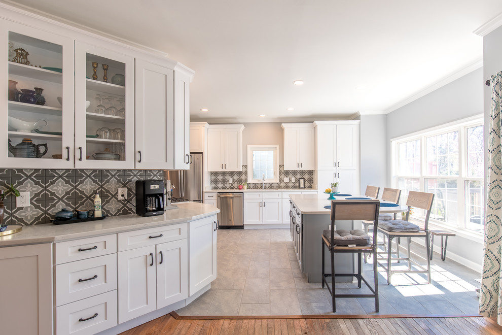 Large transitional u-shaped ceramic tile and gray floor kitchen photo in DC Metro with an undermount sink, shaker cabinets, white cabinets, solid surface countertops, multicolored backsplash, ceramic backsplash, stainless steel appliances, an island and white countertops