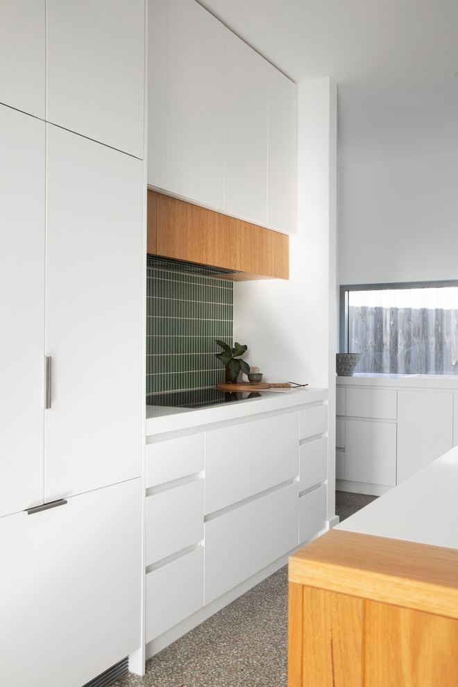 Photo of a medium sized nautical l-shaped open plan kitchen in Melbourne with a submerged sink, flat-panel cabinets, white cabinets, engineered stone countertops, green splashback, ceramic splashback, integrated appliances, concrete flooring, an island, grey floors and white worktops.